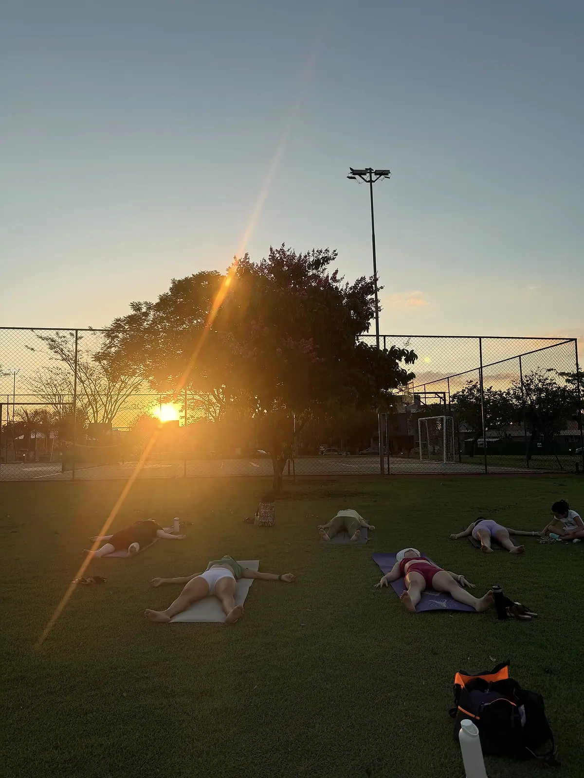Turma relaxando em savasana ao pôr do sol, ao ar livre