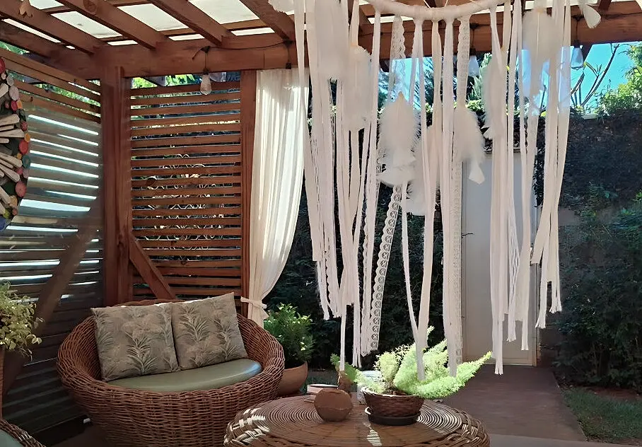 Pergolado com poltronas de fibra natural e móbile de tecidos